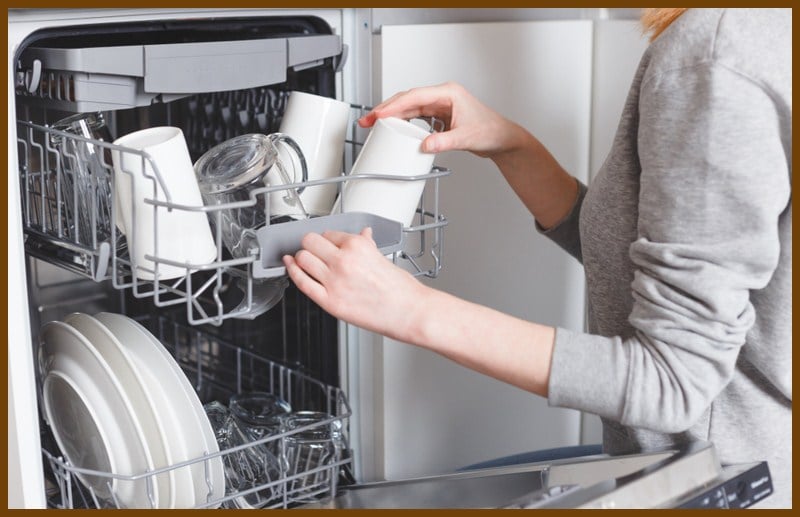 A woman putting travel mugs in the dishwasher